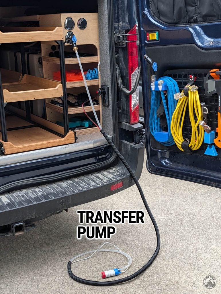 Transfer pump deployed at the van's rear Aquor fill inlet, hose and power cable bundled in black split loom