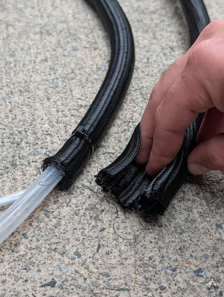 Clear water hose and power cable running side by side inside 1 inch split loom tubing