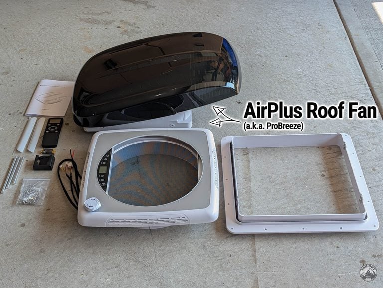 AirPlus (ProBreeze) roof fan unboxed: black lid and fan unit, white interior trim with control panel, roof flange, remote, drive shafts and hardware
