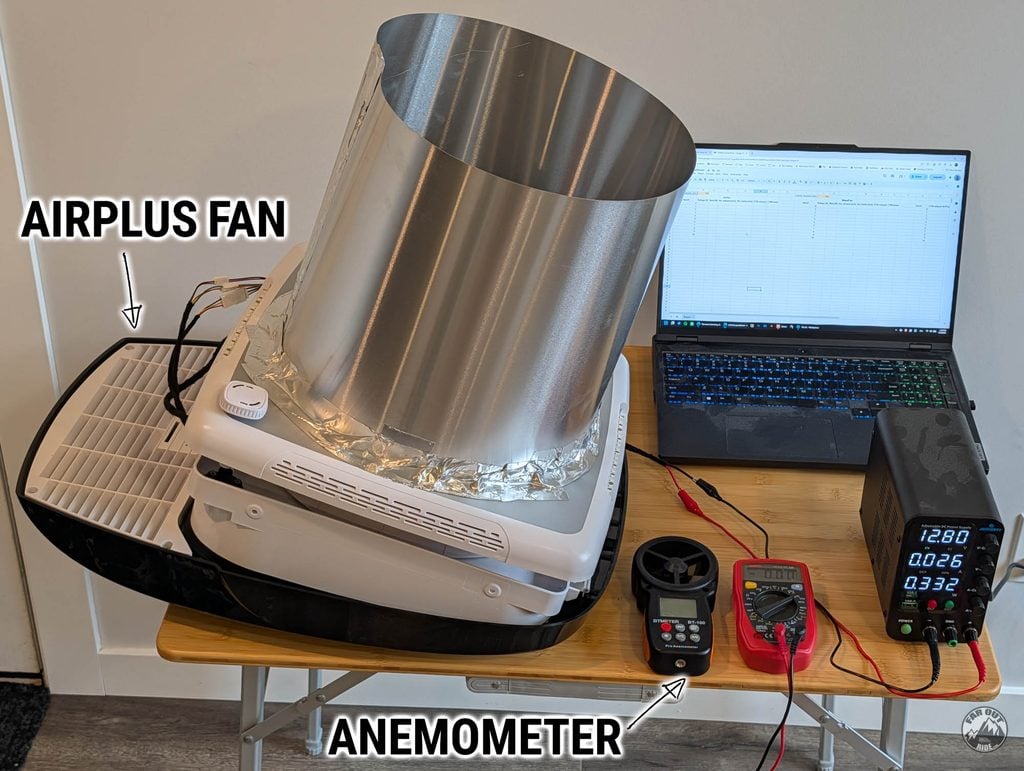 AirPlus fan on the test bench with the Ø315 mm aluminum-flashing cylinder taped over the outlet, anemometer, multimeter, bench power supply at 12.80 V and a laptop
