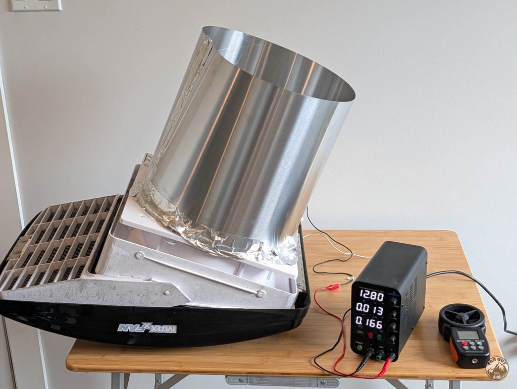 Maxxfan Deluxe on the test bench with the same aluminum cylinder over the outlet, bench power supply at 12.80 V and the anemometer