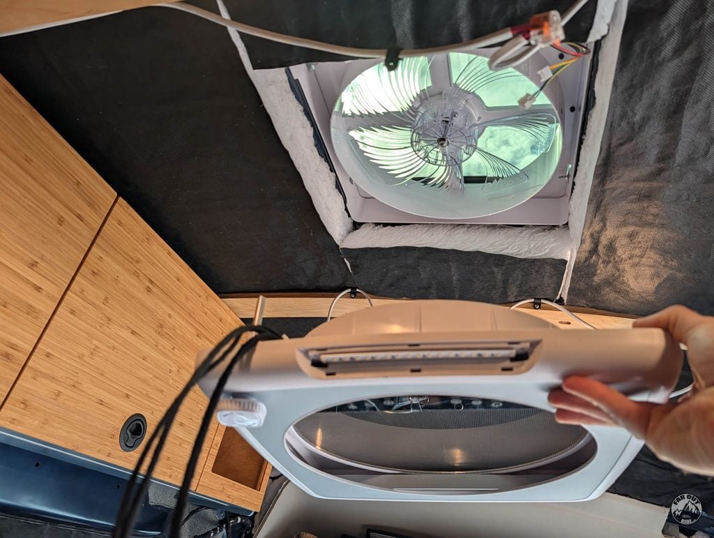 Holding the AirPlus interior cover below the open ceiling cutout in FarOutVan 2; the controls, LED lights and screen are built into the cover