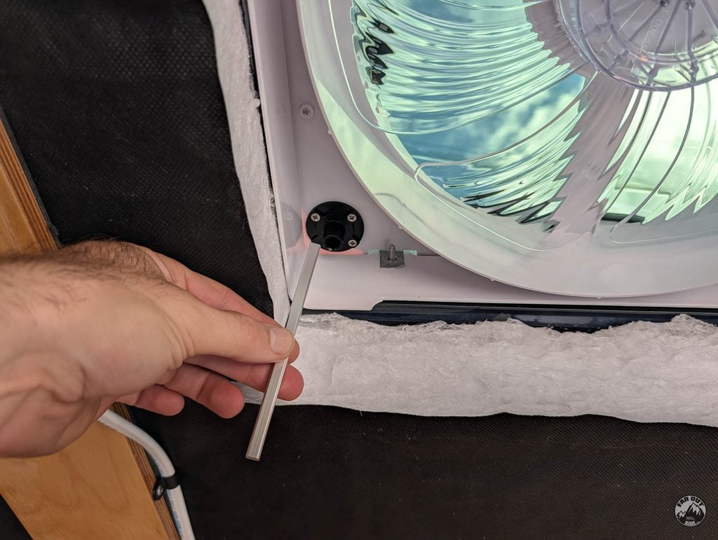 Hand holding the AirPlus lid drive shaft below the roof unit, next to the socket it engages in the ceiling opening